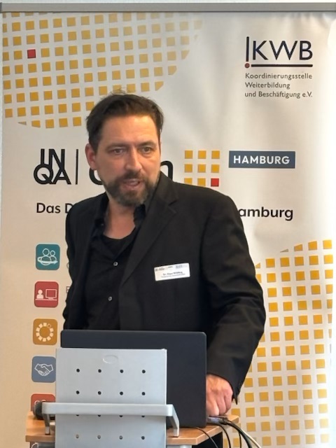 Dr. Kalus Wölfering präsentiert vor dem Banner der KWB e. V.